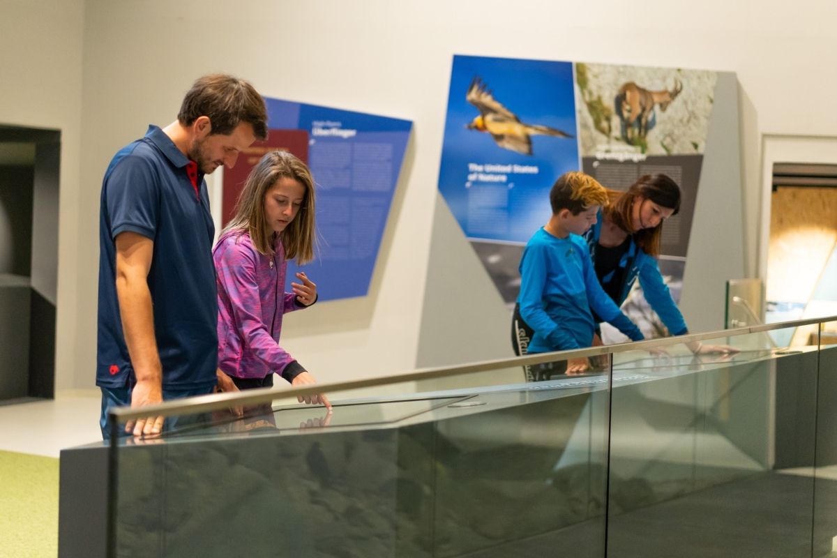 Familie bedient einen Monitor in der Ausstellung im Haus der Steinböcke